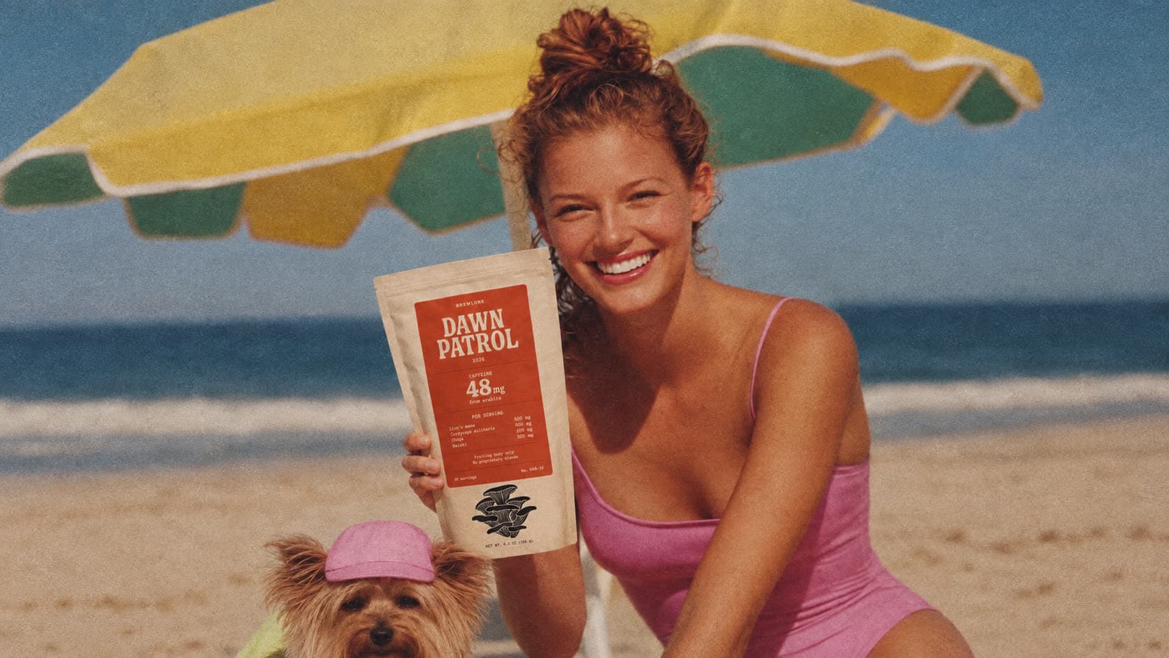 A woman under a striped beach umbrella holding a bag of Dawn Patrol, its dose table facing the camera